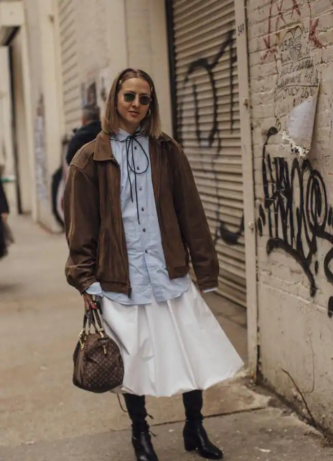 Un look con camisa azul, falda con volumen, botas y chaqueta de ante.Foto: Launchmetrics spotlight.