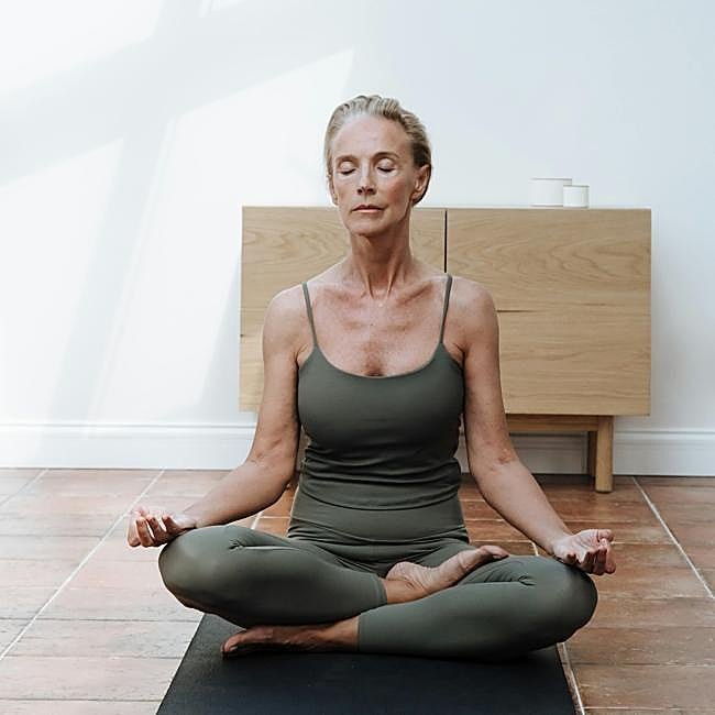 Mujer practicando yoga en casa.