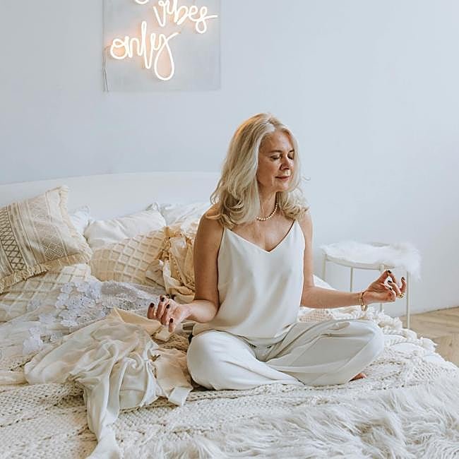 Mujer practicando yoga en su cama.