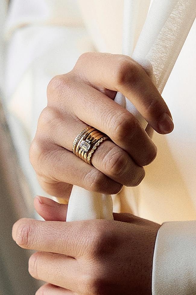 En el centro, una sortija de líneas elegantes, coronada por un diamante central, acompañado por cuatro diamantes que lo enmarca.