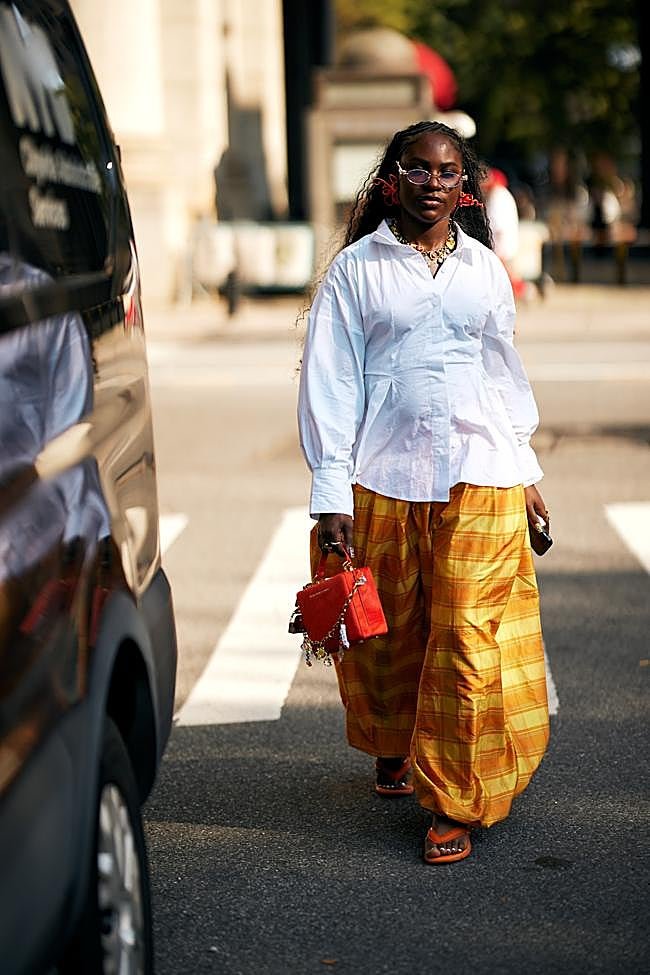 Un look con chanclas, pantalones bombacho de cuadros y camisa blanca.